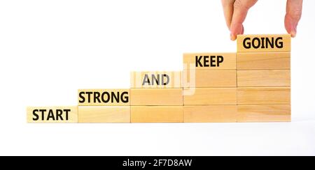 Start strong and keep going symbol. Concept words 'Start strong and keep going' on wooden blocks on a beautiful white background. Businessman hand. Bu Stock Photo