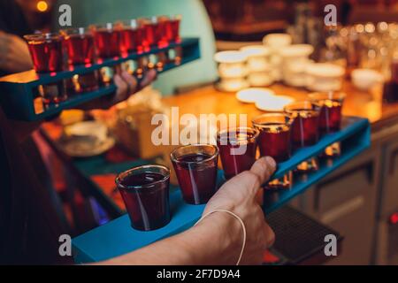 Waiter with tray takes empty beer glasses and brings cocktails to the guests of restaurant on the summer terrace. Service in cafes and restaurants. Ma Stock Photo