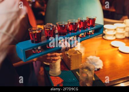 Waiter with tray takes empty beer glasses and brings cocktails to the guests of restaurant on the summer terrace. Service in cafes and restaurants. Ma Stock Photo