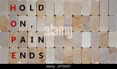 HOPE, hold on, pain ends symbol. Wooden cubes with words 'HOPE, hold on, pain ends. Beautiful wooden background, copy space. Business, motivational an Stock Photo