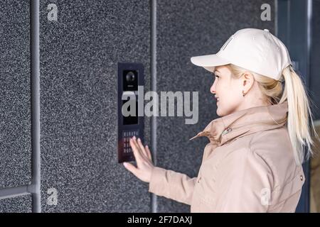 Close up the female hand presses the doorphone button. The girl is calling the intercom. Means of communication or notification of arrival and Stock Photo