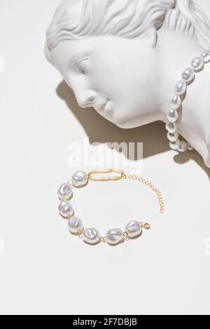 Trendy pearls and gold jewelry on plaster sculpture of woman face. Gypsum copy of heads ancient statue Venus de Milo Stock Photo