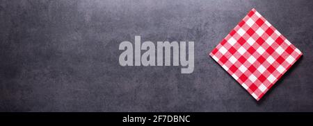 Folded checked or checkered tablecloth at stone surface of table. Top view as panorama of cloth napkin texture background with copy space Stock Photo