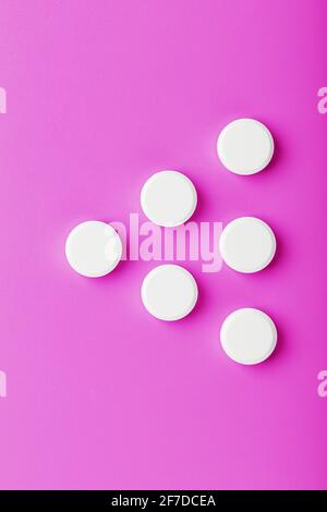 White Ecstasy pills in a row on a pink background, isolate. Top view, place for text. Stock Photo