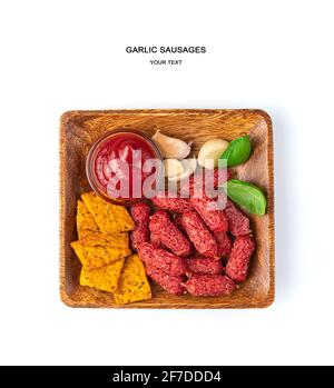Wooden square plate with snacks isolated on a white background. Smoked garlic small sausages and tomato crackers with sea salt. Stock Photo