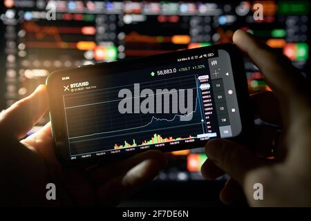 Venice, Italy - 06 April 2021: Businessman is checking Bitcoin price chart on digital exchange on mobile phone screen, cryptocurrency future price Stock Photo