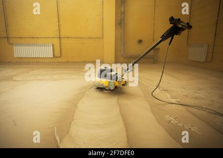Concrete floor grinding. Construction process. Sanding a concrete floor with a sander in a warehouse Stock Photo
