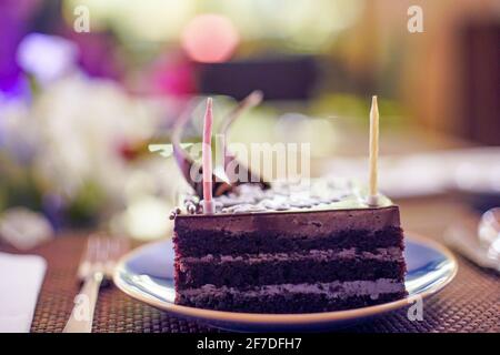 shot of cake with sparkling candles with flames and sparks flying out with an out of focus background of flowers, lights showing a birthday Stock Photo