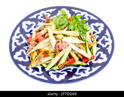 Delicious veal salad with cucumbers and avocado on authentic oriental plate. Isolated on a white background. Stock Photo