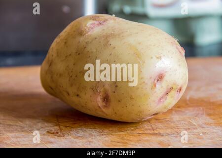 Large Baking Potato on a Chopping Board ready to prepare to be baked in the oven Stock Photo