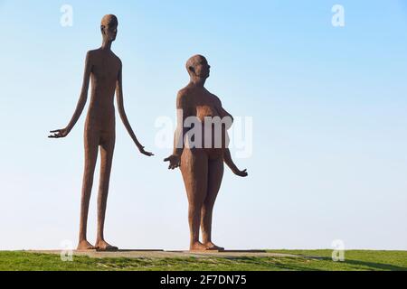 Waiting for high tide is a statue of Jan Ketelaar on the seawall near Holwerd. The two welded metal, five meters high women look out over the sea. Stock Photo