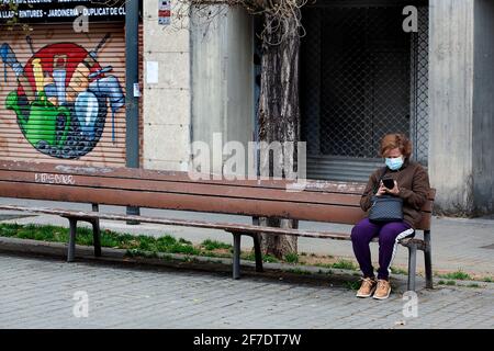 Woman sat alone on bench looking at her phone, Barcelona, Spain. Stock Photo