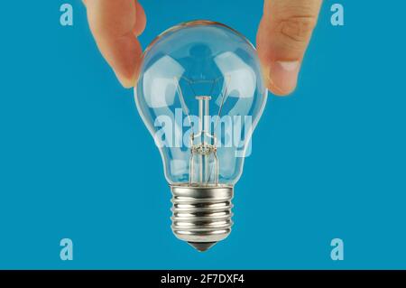 Hand holding a light bulb with blue background. Concept and idea background. Stock Photo