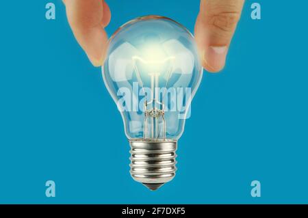 Hand holding glowing a light bulb with blue background. Concept and idea background. Bright idea. The way to solve problem. Stock Photo