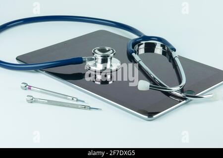 Stethoscope on the tablet and screwdrivers. Tablet repair and service concept. Concept a health of device. Stock Photo