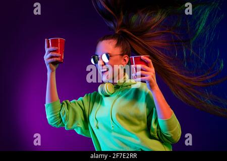 Photo of sweet shiny young lady wear green sweater holding two red paper glasses dancing isolated colored bright shine background Stock Photo