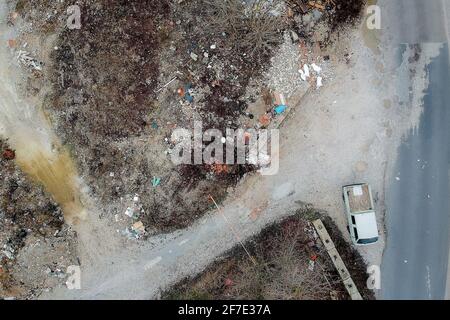 An illegal dumping ground of construcion trash seen from above. Concept of illegal dumping of trash with a visible delivery van on the side of the roa Stock Photo