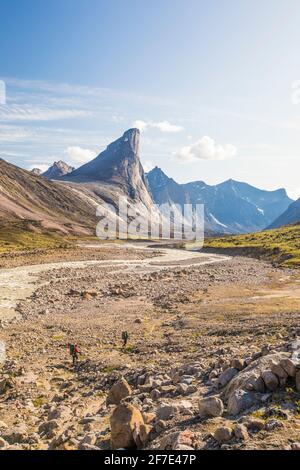 Two backpackers hike in the valley below Mount Thor, Baffin Island. Stock Photo