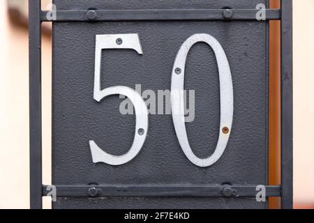 The number 50 (fifty) in metal screwed on a black metal plate Stock Photo