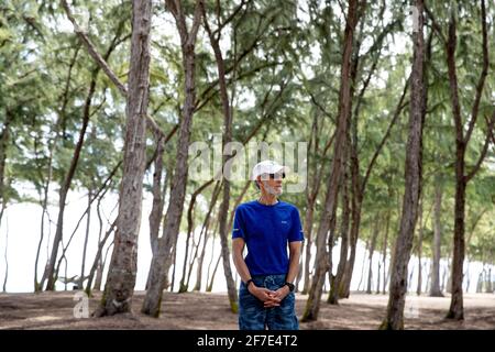 Older man visiting Hawaii standing peacefully in a sea of trees Stock Photo