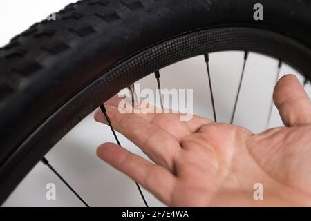 Bicycle tube repair. A hand of a person is deflating a presta valve on a mountain bike wheel. Stock Photo