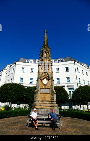 Men sitting on bench in front of the Edward Hoare memorial on corner of Culverden Park and St John's Road, Royal Tunbridge Wells, Kent, England Stock Photo