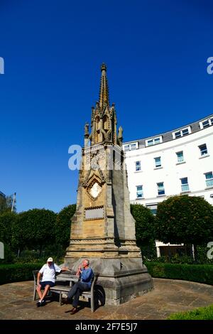 Men sitting on bench in front of the Edward Hoare memorial on corner of Culverden Park and St John's Road, Royal Tunbridge Wells, Kent, England Stock Photo