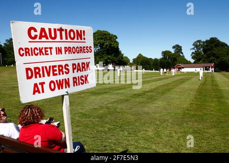 Sign warning drivers that they park next to the cricket ground at their own risk while a match is in progress, Southborough Common, Kent, England Stock Photo