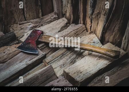 Hatchet axe lying on a pile of split wood logs used for fire. Concept of making logs portrayed in natural colors- Axe viewed from the top side with a Stock Photo