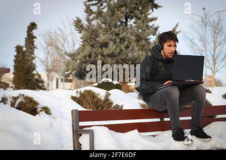 Dark-haired millennial college boy studying on laptop with headphones Stock Photo