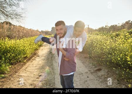 happy father looks at camera while playing with his son on the field Stock Photo