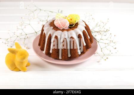 Easter cake and and Easter Bunny on a white wooden background. Sweets for celebrating Easter. Stock Photo