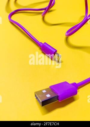 purple usb cord on bright yellow background vertical orientation Stock Photo