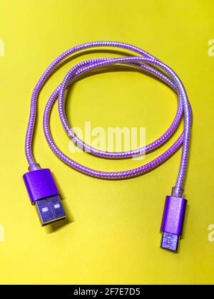 purple usb cord on yellow background vertical orientation Stock Photo