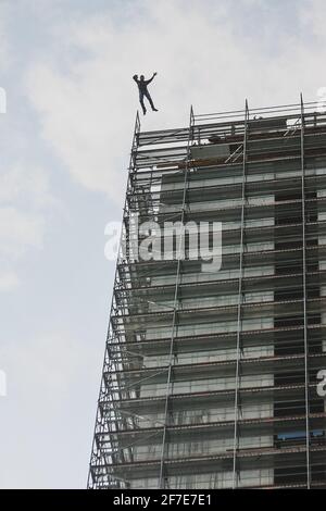 Silhouette of a person jumping from the top of a building that is still under construction. Base jump from a skyscraper. Stock Photo