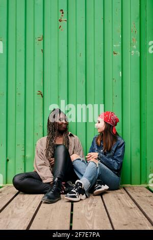 Two young multiethnic women talk and smile Stock Photo