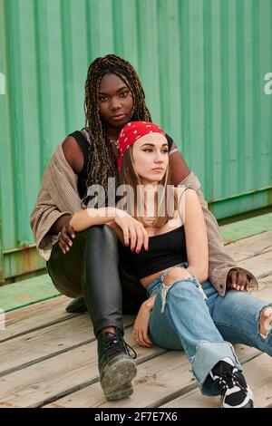 Multiethnic women embracing in urban clothing pose facing the camera Stock Photo