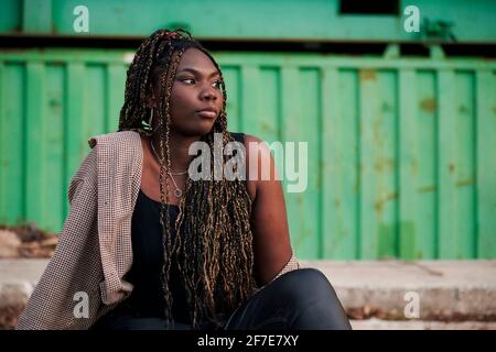 Black woman in urban clothing is sitting on abandoned train tracks Stock Photo