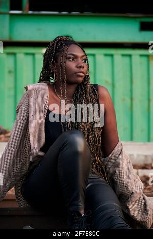 Black woman in urban clothing is sitting on abandoned train tracks Stock Photo