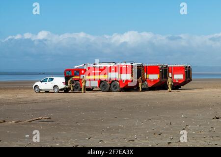 CEFN SIDAN, WALES - MARCH 25 2021: Multiple Airport fire trucks provide safety cover for the Royal Air Force as its practices tactical beach landings Stock Photo