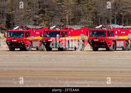 CEFN SIDAN, WALES - MARCH 25 2021: Multiple Airport fire trucks provide safety cover for the Royal Air Force as its practices tactical beach landings Stock Photo