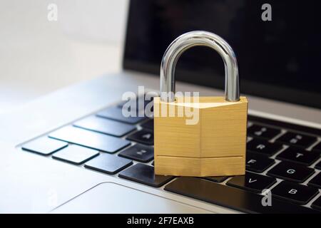 A lock on top a computer keyboard. Concept: cybersecurity, protection of computer systems and networks from information disclosure. Stock Photo