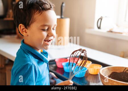 A little boy licks a whisk with chocolate dough Stock Photo