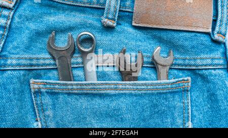 A set of small wrenches fits in a jeans pocket. The kit is used for repair and construction. Present in the photo: phantom blue and metallic color. Ph Stock Photo