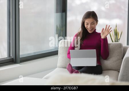Working from home Asian woman on remote work online video meeting waving hello to her colleagues on webinar live stream videocall videoconference Stock Photo