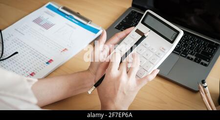Close up of woman calculating financial or taxes or household on calculator, female calculate while sitting at her home and make payment. Stock Photo