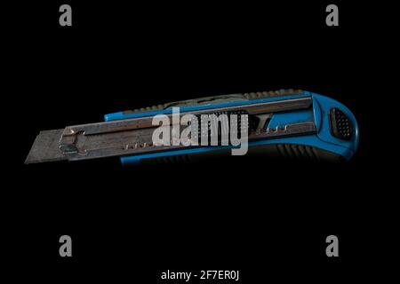 Heavily worn precision or utility knife in blue color isolated on black. Olfa knife or xacto knife against a black background. Stock Photo