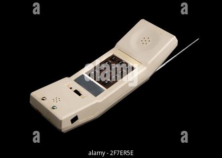 An old white vintage cordless telephone from the eighties isolated on black. Visible brown keyboard and silver antenna. Stock Photo