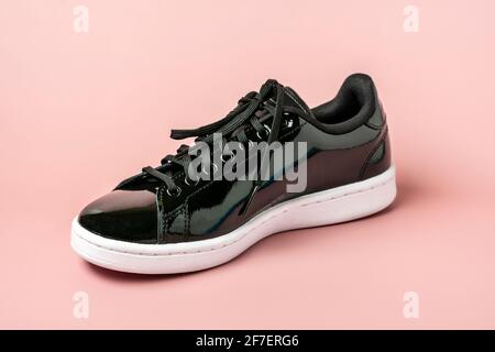patent leather black color sneakers isolated on pink background Top view flat lay Casual wear. Stock Photo