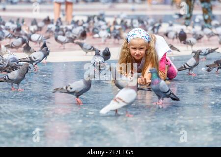 A girl 6-7 years old, feeding pigeons at Plaza de Catalunya in Barcelona. Stock Photo